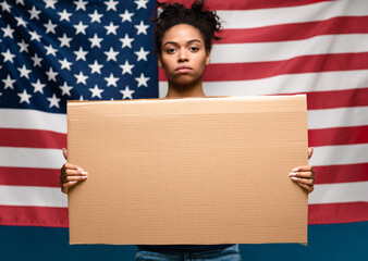 Black girl standing with blank cardboard over american flag