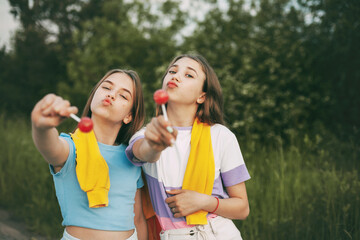 Two funny teenage girls holding a bright red lollipop candy.