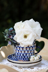 Sommerdekoration mit weißen Rosenblüten in vintage Kaffeetasse