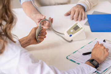 Hands of therapeutist pressing tonometer pump while measuring blood pressure
