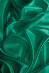 Beautiful smooth elegant wavy emerald green satin silk luxury cloth fabric texture, abstract background design. Card or banner.
