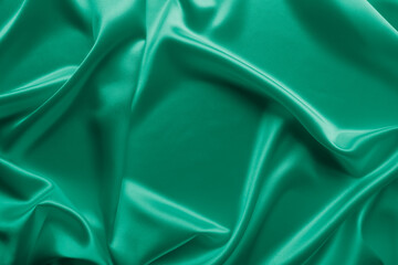 Beautiful smooth elegant wavy emerald green satin silk luxury cloth fabric texture, abstract background design. Card or banner.

