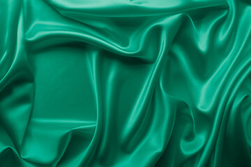Beautiful smooth elegant wavy emerald green satin silk luxury cloth fabric texture, abstract background design. Card or banner.
