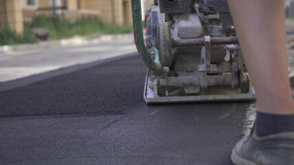 Vibratory asphalt paving machine on the sidewalk filmed close-up.Road works,pavement repair,hard work.Video clip