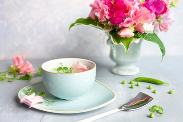 Homemade fresh green pea cream soup with pea sprouts and flowers