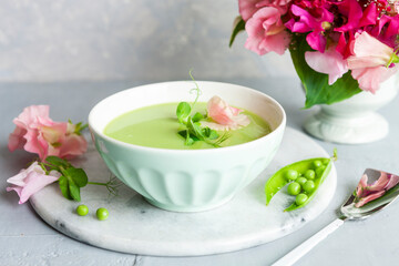 Obraz na płótnie Canvas Homemade fresh green pea cream soup with pea sprouts and flowers