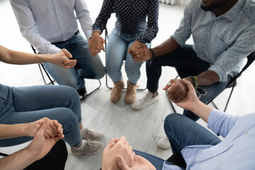 People sit in circle hold hands involved at group therapy session. Religious girls guys pray...