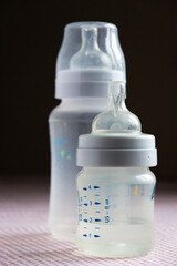 Feeding bottles with scale on dark background in kid's room