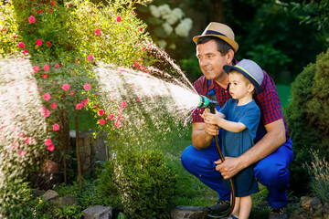 man gardener with grandson watering garden