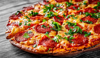 Pepperoni Pizza with Mozzarella cheese, salami, Tomato sauce, pepper, Spices and Fresh basil. Italian pizza on wooden table background