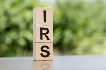 IRS word written on wooden cubes on table with green background