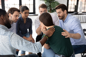 Multiethnic members supporting rehab session female participant provide her moral support. Diverse...