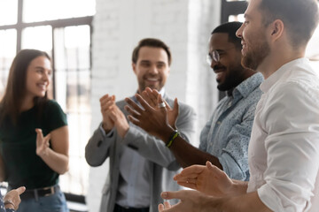 Happy enthusiastic multiracial young business people standing in modern office board room clap hands congratulating each other with successful seminar accomplishment, common victory, teamwork concept