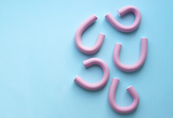 Soft pink curlers for Curling hair on a blue background. Selective focus. Hairdressing services. Copy space