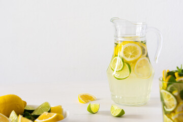 Summer refreshing drink of lemon, lime and mint, jug with lemonade and glasses and citrus slices