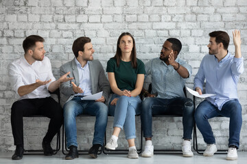 Multiracial men applicants sit on chairs in job interview queue show disrespect for girl kick out her. Disregard neglect, gender discrimination of women in business and professional occupation sphere - obrazy, fototapety, plakaty