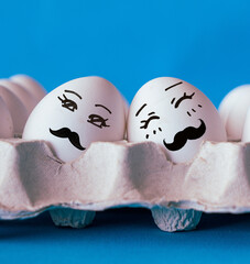 Faces on the eggs, gay couple in love concept with blue background
