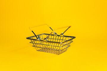 Buying concept. Shopping cart on a yellow background. Minimalist style. Creative design. Shopping cart in a supermarket