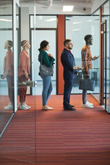 Full length side view at multi-ethnic group of business people standing in line in modern office...