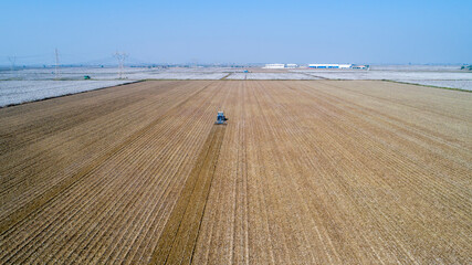 Flight over ploughed field with tractor. Industrial background on agricultural theme