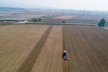 Flight over ploughed field with tractor. Industrial background on agricultural theme