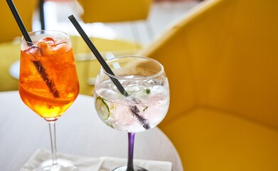 Glass of cold refreshing aperol spritz and gin tonic cocktail on table in summer. 