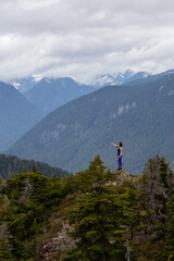 Fototapeta na wymiar Adventurous Girl on top of a Mountain top with Canadian Nature Landscape in Background. Taken on Evan's Peak, Golden Ears Provincial Park, near Vancouver, BC, Canada.