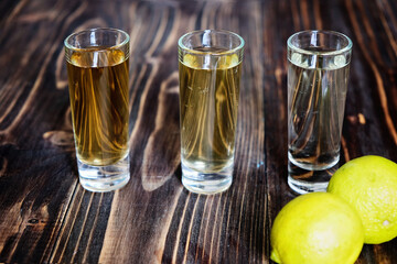 Mexican gold and silver tequila and lime on wood background