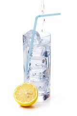 Water being poured into a glass with ice cubes and straw, orange next to it. Isolated on white. 