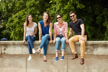 Happy young people sitting outdoors, smiling. 