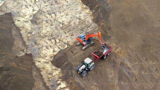 Auskoffern: Tiefbau Erdbau Bauarbeiten: Bagger verl&auml;dt Erde, Sand auf einen Muldenkipper, Luftbild