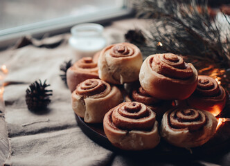 Cinnamon rolls. Cinnabon for Christmas. Homemade traditional winter pastry on dark wooden background. Kanelbulle - swedish cinnamon rolls in christmas setting.