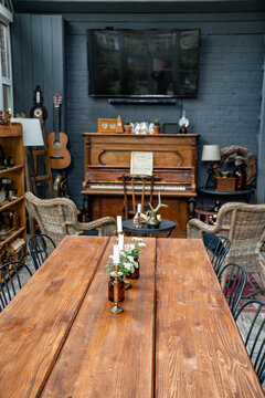 Table With Candles And Flowers In Room With Piano. Interior In Retro Style.