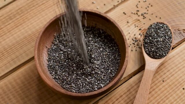 Slow motion chia seeds fall in bowl. Healthy superfood rich in Omega 3 fatty acids