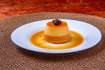 Homemade milk pudding with caramel cream. Traditional Brazilian dessert on a plate on wooden...