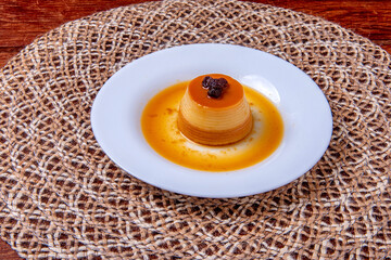 Homemade milk pudding with caramel cream. Traditional Brazilian dessert on a plate on wooden background.