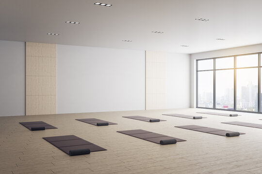 Minimalistic interior of yoga classroom with mats and city view.