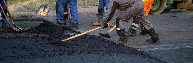 Asphalting and road repairs. The team of construction workers repairing roads.