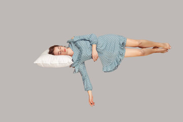 Sleeping beauty hovering in air. Relaxed girl in vintage ruffle dress lying comfortably on pillow...