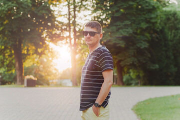 portrait of a young guy in sunglasses in a summer park