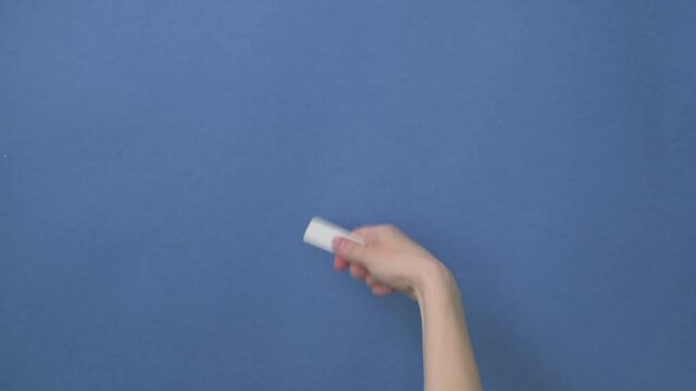 A close-up holds a white eraser in his hand. Hand erases written information.