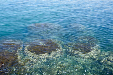 Fototapeta na wymiar Stones in blue turquoise water in Crete, Greece