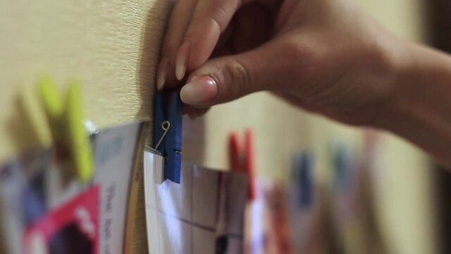 Four colored paper square frame on a clothesline and clothespins in the hands of a girl.