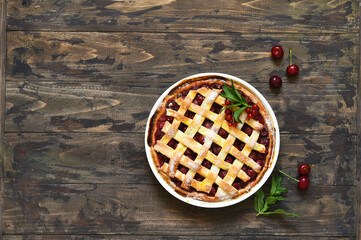 Cherry pie on a wooden background with place for text. View from above.