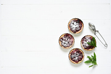 Tartlets with berries on a white wooden background. View from above.