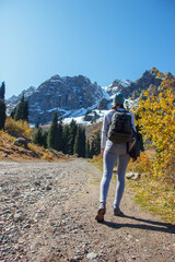 Obraz premium A slender girl with a large backpack takes a hiking walk to the mountain top.