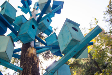 Lots of blue wooden birdhouses on a tree. Condominium concept.