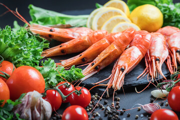 Large fresh prawns. Seafood with vegetables and herbs. Tomatoes and salad. Still life on a dark background.