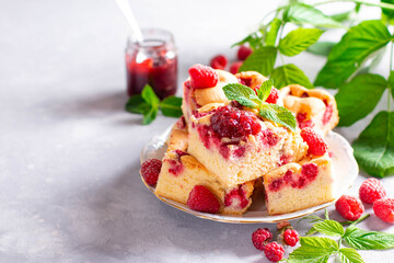 Pieces of homemade raspberry cake on a plate with fresh raspberry berries and mint. Copy space