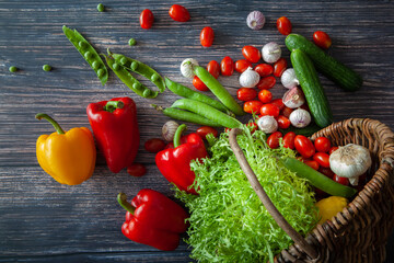 Still life with various types of fresh vegetables in a basket on a table. Top view.
